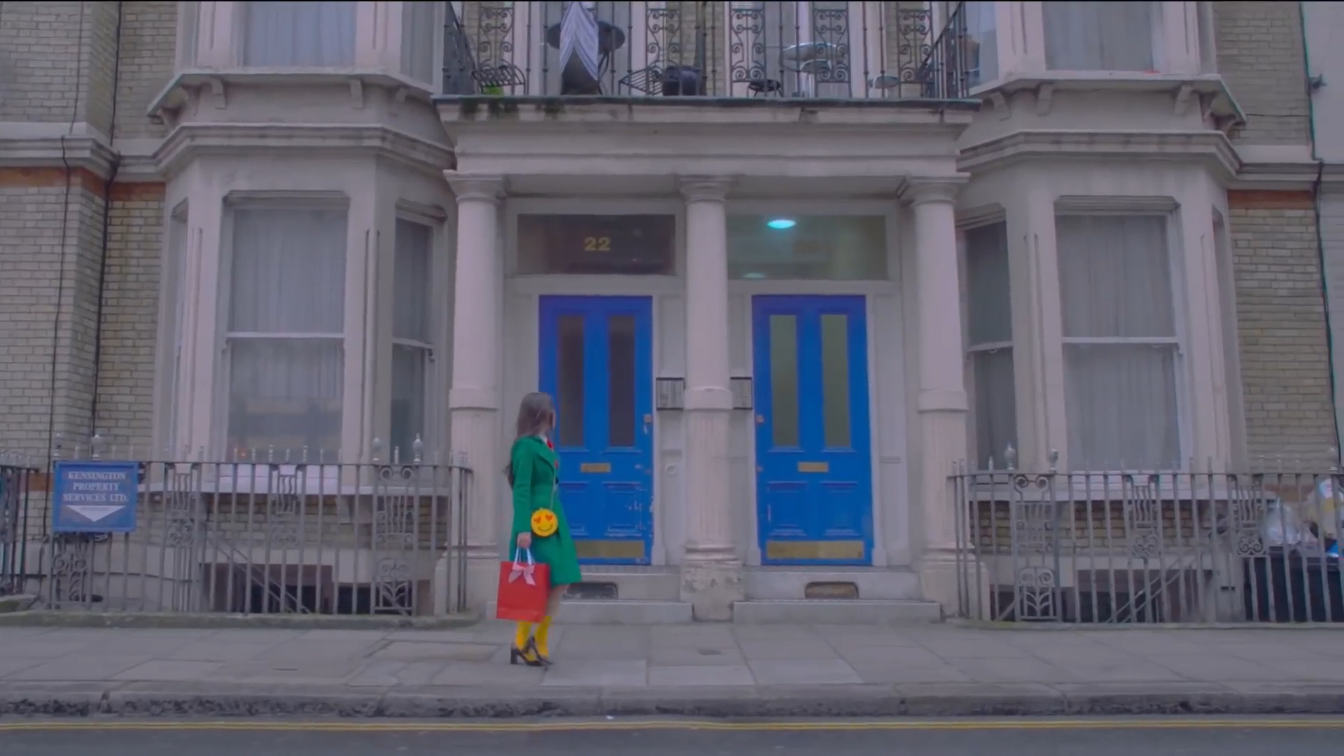 Heejin walking by two blue doors.